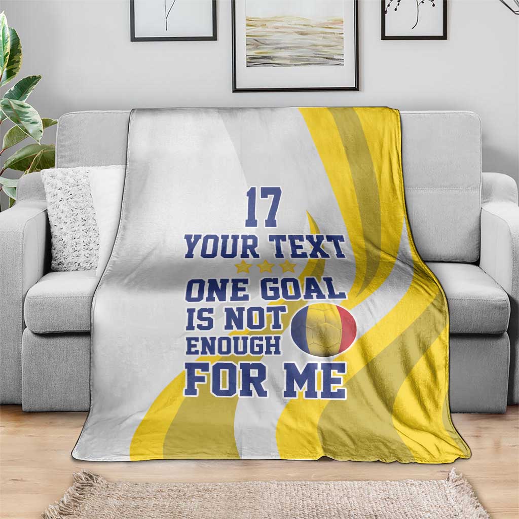 Football blanket on sofa, white with yellow stripes and “ONE GOAL IS NOT ENOUGH” text