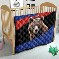 Quilt blanket with brown bear face and Russian flag pattern, on a baby bed