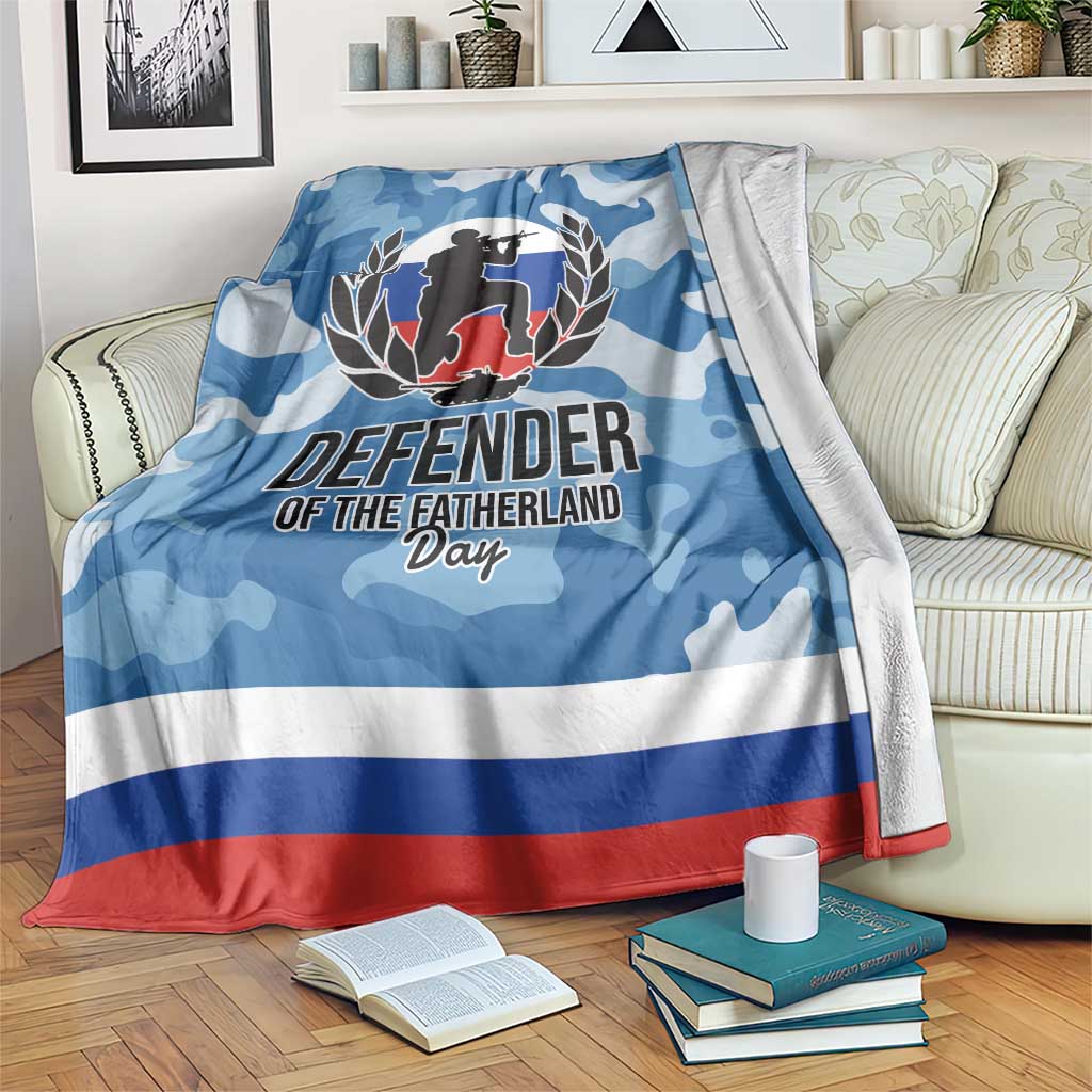 Blue camouflage blanket draped over sofa, Defender graphic and red/white bottom border