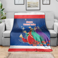 Blue Three Kings Day blanket draped on couch, red-and-white border, kings illustration