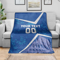 Blue blanket on a grey couch with white diagonal design, “YOUR TEXT 00,” and Colosseum