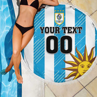 Round beach blanket showing Uruguay crest and sun graphic on blue-and-white stripes