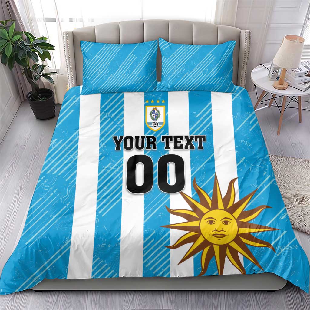 Blue bedding set with white vertical stripes, sun artwork, crest, and "YOUR TEXT 00".