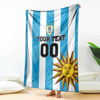 Hanging blue and white striped football blanket with Uruguay crest, sun graphic, and 'YOUR TEXT 00'.