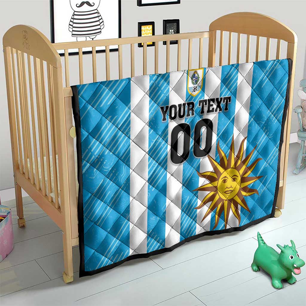 Blue football quilt in crib with white stripes, crest logo, sun graphic, and custom 00