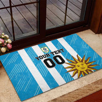 Blue striped rubber doormat with 'YOUR TEXT 00', Uruguay crest, and sun design.