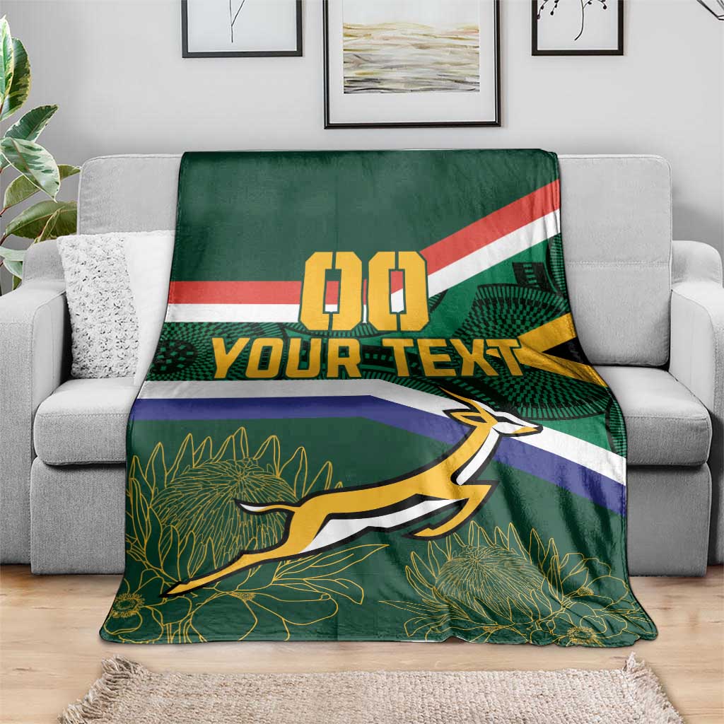 Green blanket on gray sofa, flag stripes, 00 and YOUR TEXT, springbok over leaf pattern