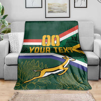 Green blanket on gray sofa, flag stripes, 00 and YOUR TEXT, springbok over leaf pattern
