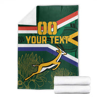 Green blanket folded with 00, YOUR TEXT, flag stripes and springbok leaf design