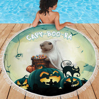 Round green Halloween beach blanket with capybara holding candy, pumpkins, and fringed border