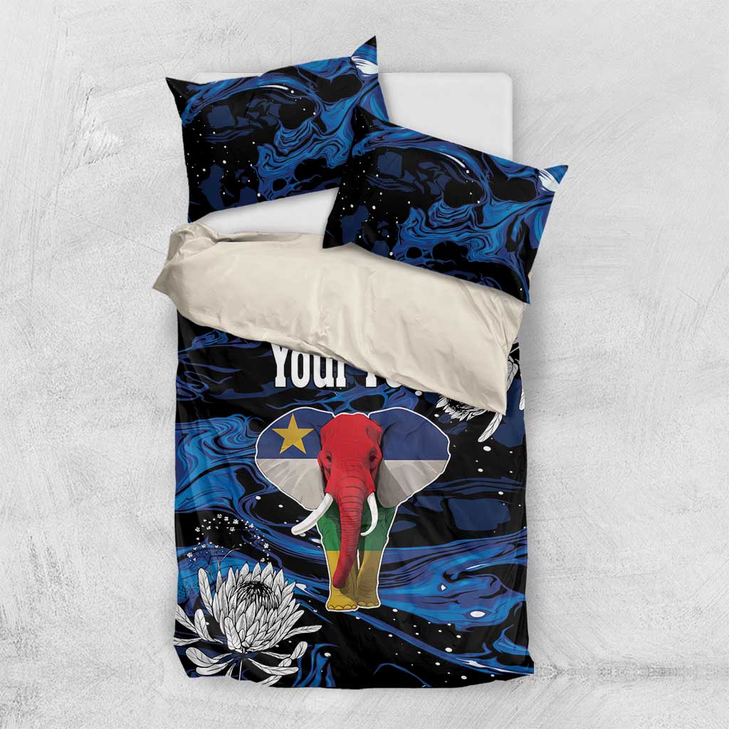 Flat lay king bedding set with blue-black elephant print, protea blooms, and two pillows