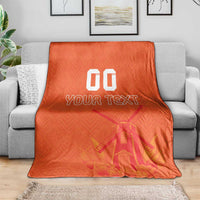 Orange rugby blanket on a couch, windmill and tulip pattern with 'YOUR TEXT' and '00'
