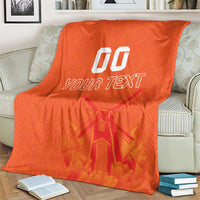 Orange rugby blanket on an armchair, windmill and tulip pattern with 'YOUR TEXT' and '00'