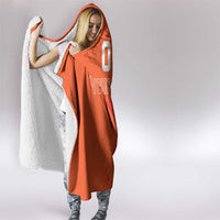 Orange hooded blanket with hood and jersey-style graphic, white text on front