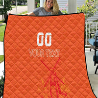 Orange quilt blanket close-up with custom jersey text and number graphic, diamond stitched texture.