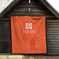 Orange quilt blanket displayed under a wooden shelter, featuring custom jersey text and number graphic.