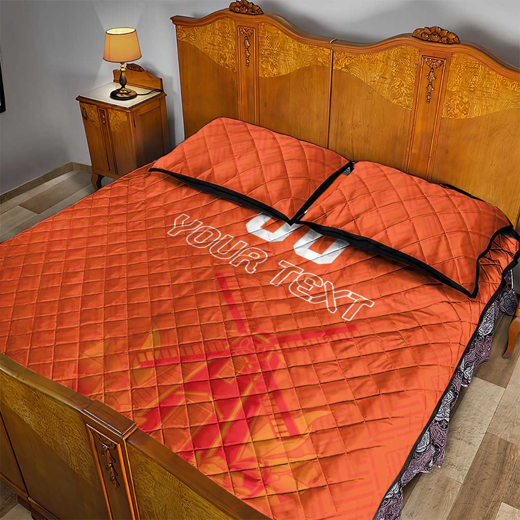 Orange quilt bed set with black-trim edges, two pillows, and 'YOUR TEXT' lettering