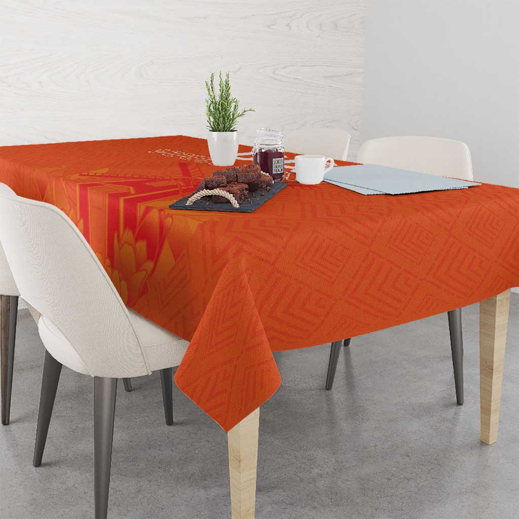 Orange tablecloth with windmill and tulips jersey pattern draped over dining table with place settings