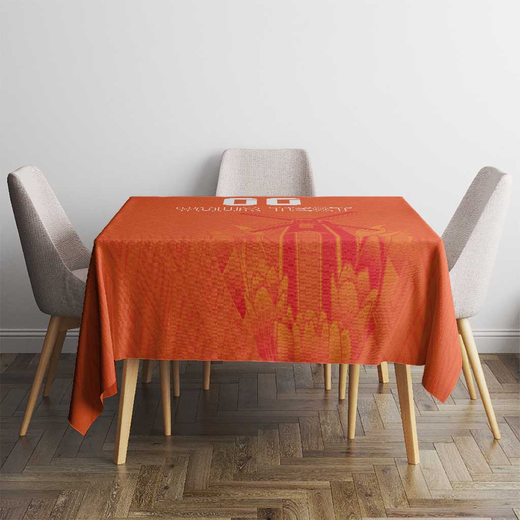 Orange tablecloth with windmill and tulips jersey pattern on table with four chairs