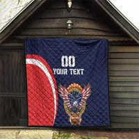 Blue quilt with red-and-white arc stripe, eagle-and-football emblem, custom text.