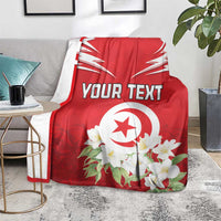 Red Tunisia blanket on floor with white emblem, jasmine flowers, and custom text