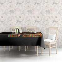 Black tablecloth with colorful geometric trim and lion artwork on a dining table