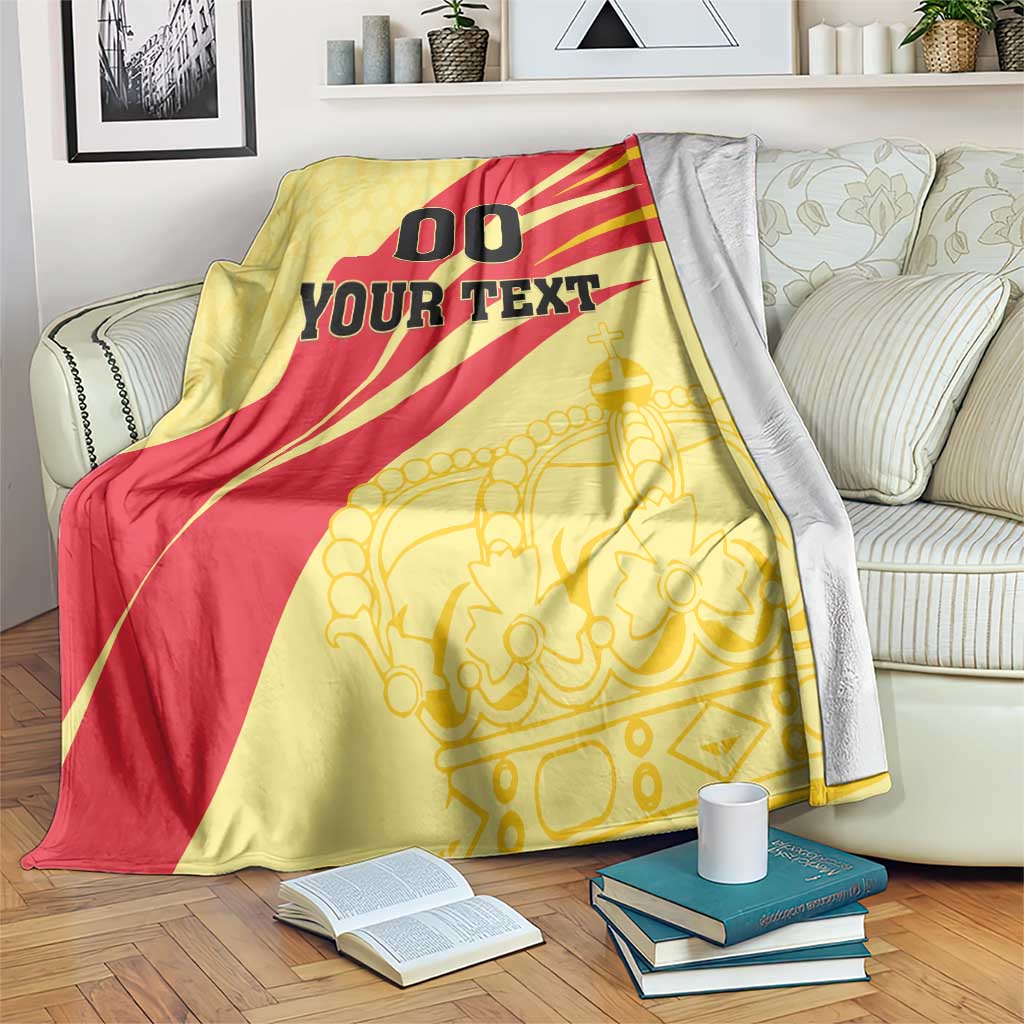 Spain football blanket draped on couch, yellow/red '00 YOUR TEXT' with gold crown