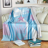 Folded blue sports blanket on sofa, showing “00 YOUR TEXT” and star crest design