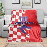 Red and white checkered blanket on a gray couch, featuring blue “00” and custom text