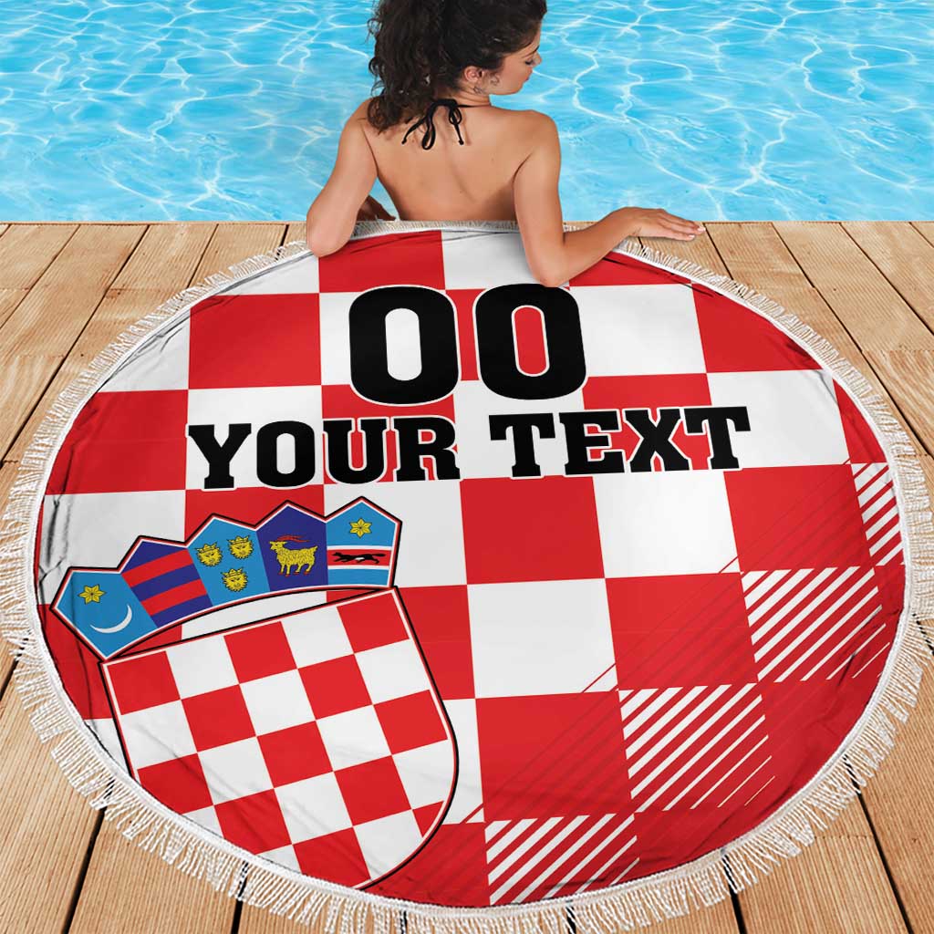 Red-and-white checkerboard round beach blanket with coat of arms graphic and white tassel fringe