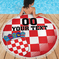 Red-and-white checkerboard round beach blanket with coat of arms graphic and white tassel fringe