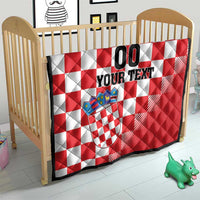 Red and white checkerboard quilt with coat of arms emblem on a baby crib