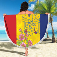 Round beach blanket with white fringe, yellow red blue eagle/crest artwork with flowers.