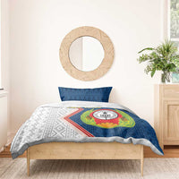 Blue and white bedding set with emblem centered on duvet and patterned pillowcases.