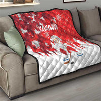 Red and white Santa and Canada quilt draped over a gray sofa with snowflake pattern