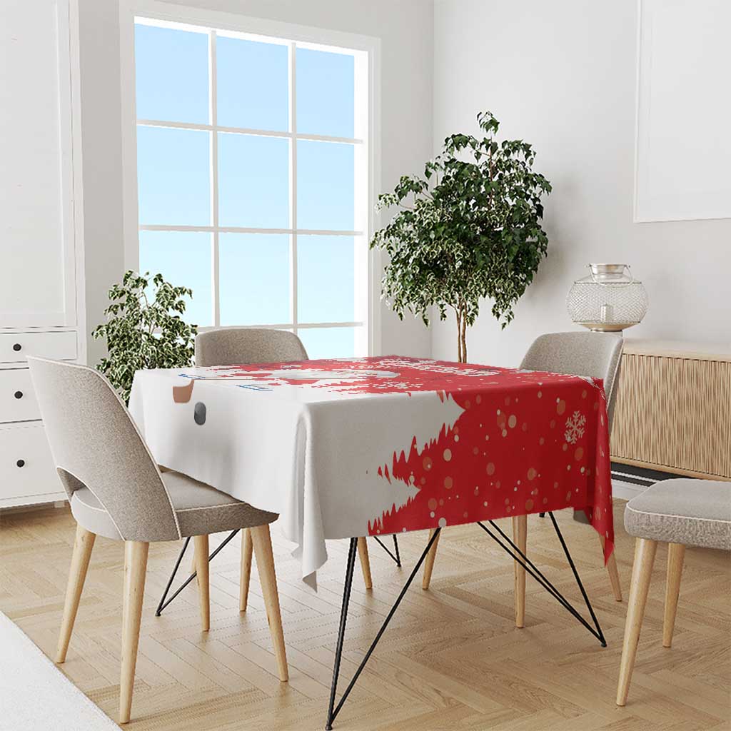 Red and white Christmas tablecloth draped on dining table with Santa and tree motifs