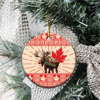 Round ceramic moose ornament with red maple leaf design, hanging on a tree branch
