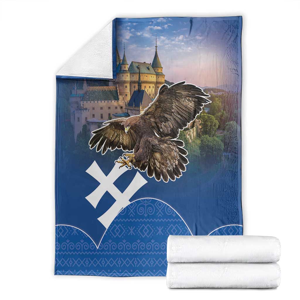 Folded blue eagle and castle blanket with white cross design and Slovak-style pattern