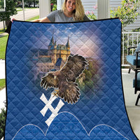 Blue quilt with diamond stitching, castle scene, eagle graphic, and white cross motifs