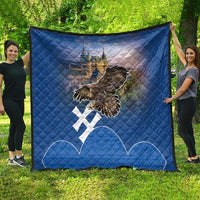 Blue quilt spread on grass featuring castle image, flying eagle, and white cross symbols