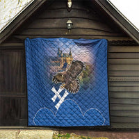 Blue quilt hanging on wall showing castle artwork, eagle design, and white cross accents