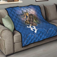 Blue quilt on gray couch featuring castle scene, eagle artwork, and white cross pattern