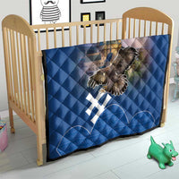 Blue quilt on baby bed with castle image, eagle graphic, and white cross motifs