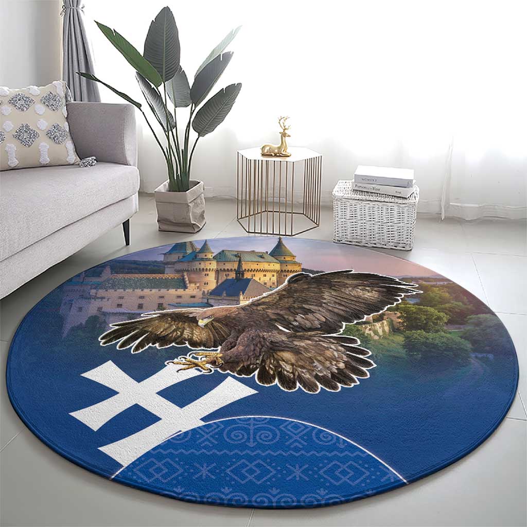 Round blue area rug with brown eagle wings spread, castle skyline, and white cross design