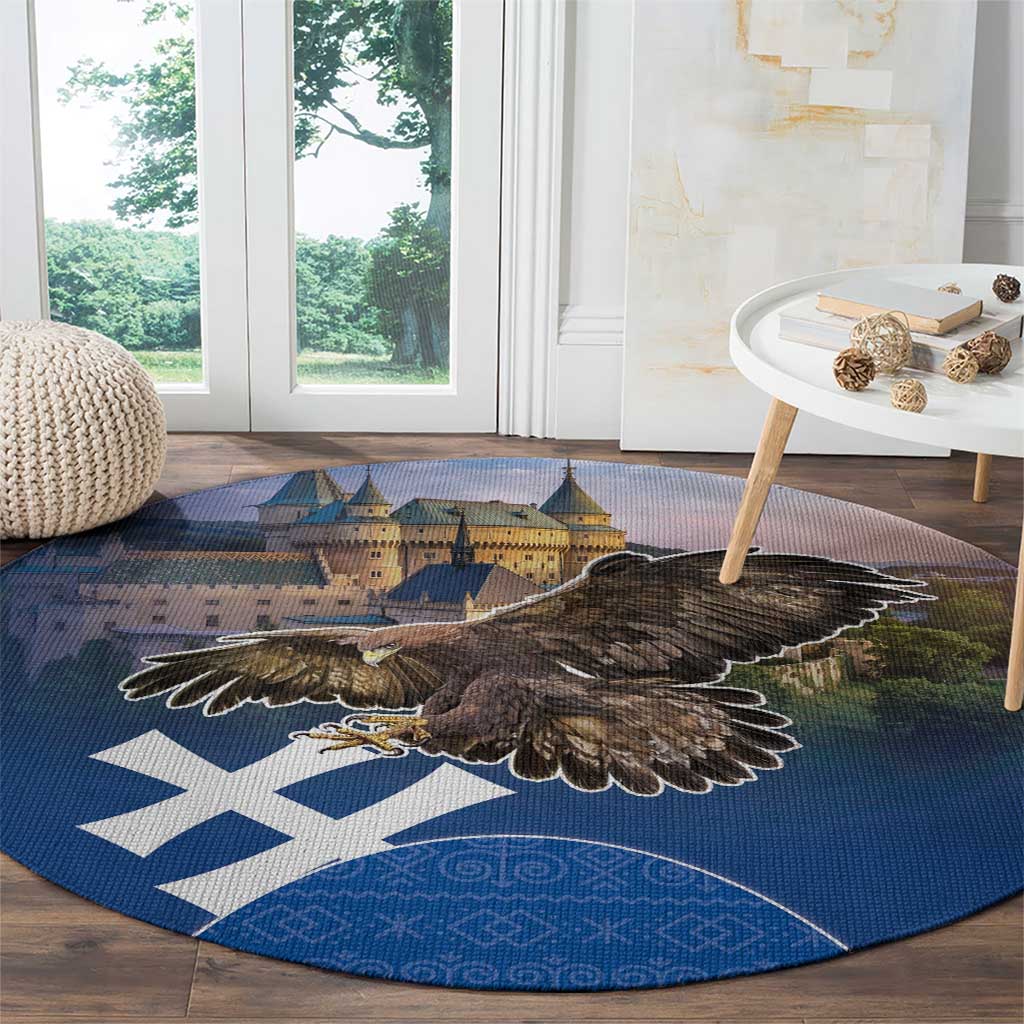 Round blue area rug with large brown eagle over castle image and white cross motifs