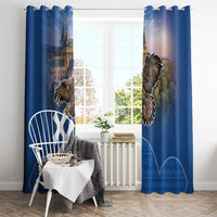 Blue window curtains with top hooks and castle-eagle print over a white-framed window