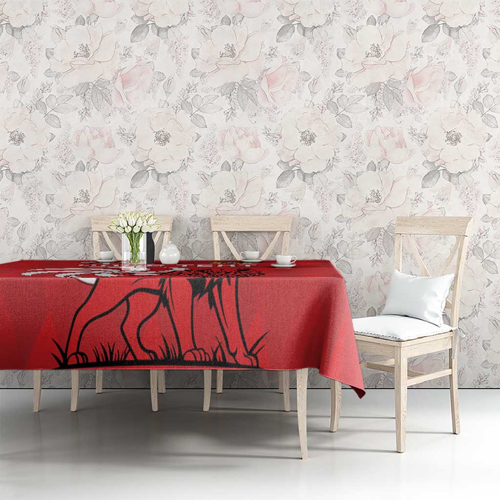 Red tablecloth with lion illustration over dining table with chairs