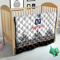 White quilt on a baby bed with blue 00 crest, red YOUR TEXT, black quilted edge