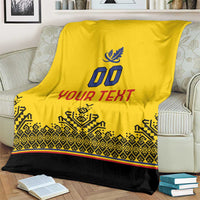 Yellow blanket draped with blue crest, '00', 'YOUR TEXT', and black patterned border.
