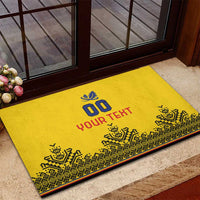 Yellow rubber doormat on steps with blue leaf '00', red 'YOUR TEXT' and dark border.